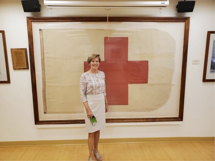 Red-Cross-Flag Photo: Diane Peters-Nguyen stands in front of the Red Cross flag