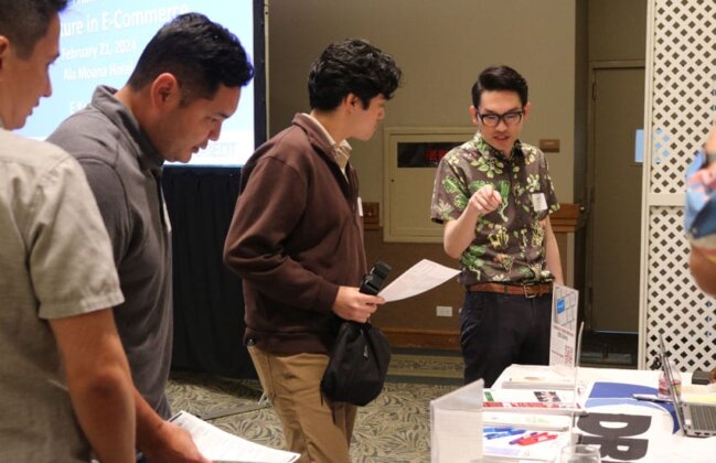 Photo: Conference participants visit the DEBT Exhibit booth