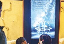 Sailing the Wake of the Past; Charting the Next Voyage Photo: Young visitors to the "Wayfinders" exhibit hold shells to their ears to hear the sound of the ocean